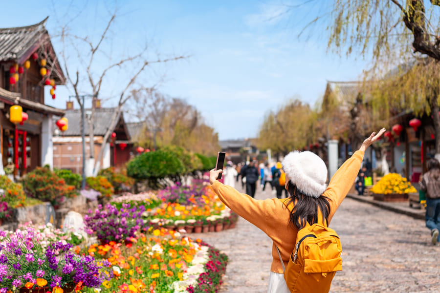Turista con los abrazos abiertos en un camino con flores